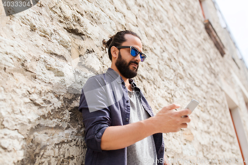 Image of man texting message on smartphone at stone wall