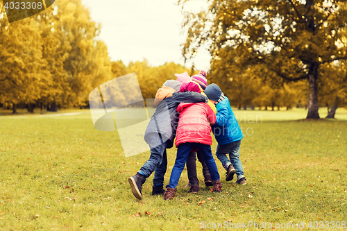 Image of group of happy children hugging in autumn park