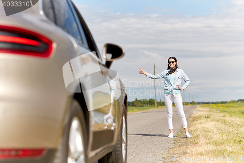 Image of woman hitchhiking and stopping car at countryside