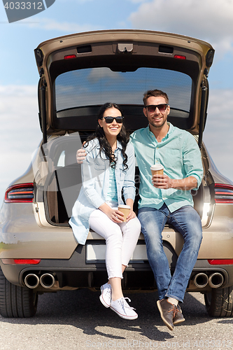 Image of happy couple with coffee at hatchback car trunk