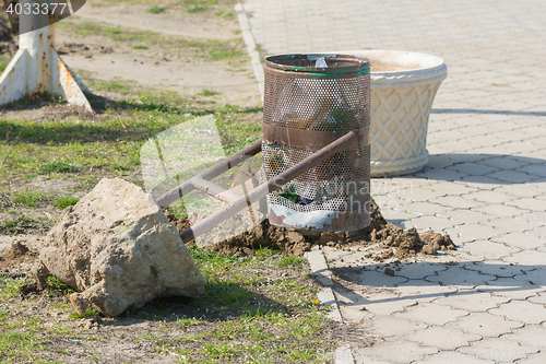 Image of Torn out of the earth a broken wheelie bin with concrete base