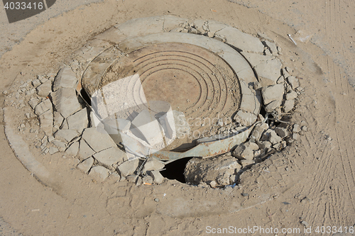 Image of Destroyed well with cast iron lid on the dusty road