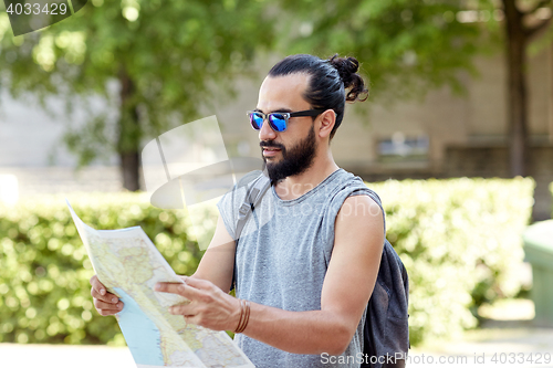 Image of man traveling with backpack and map in city