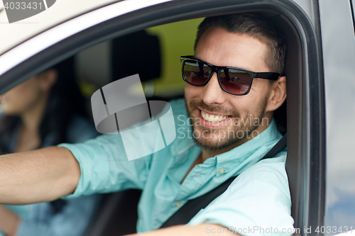 Image of happy smiling man in sunglasses driving car