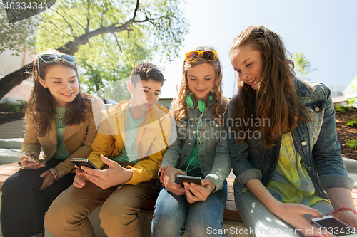 Image of happy teenage friends with smartphones outdoors