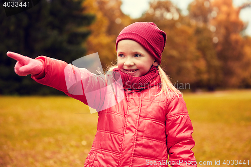 Image of happy little girl pointing finger in autumn park