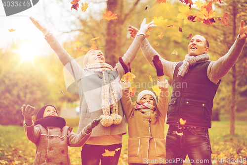 Image of happy family playing with autumn leaves in park