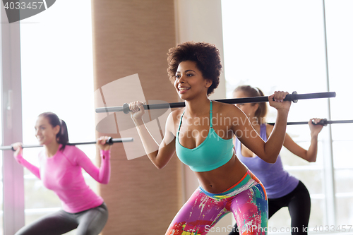 Image of group of people exercising with bars in gym