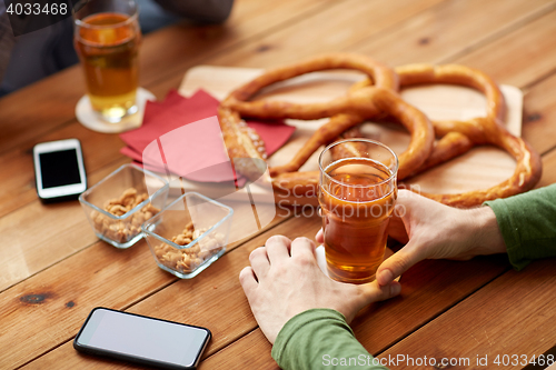 Image of close up of hands with smartphones and beer at bar