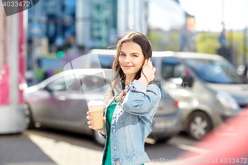 Image of happy young woman drinking coffee on city street