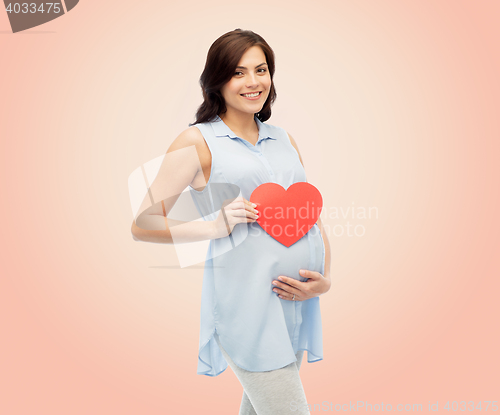 Image of happy pregnant woman with red heart touching belly