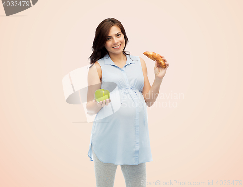 Image of happy pregnant woman with apple and croissant