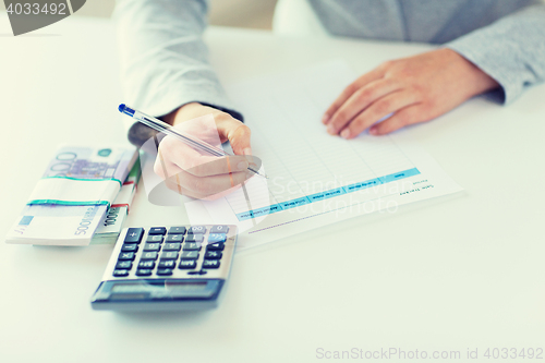 Image of close up of hands counting money with calculator