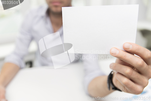 Image of close up of businessman with blank paper at office