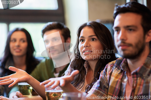 Image of friends with beer watching football at bar or pub