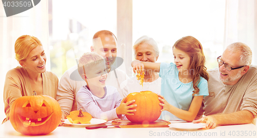 Image of happy family sitting with pumpkins at home