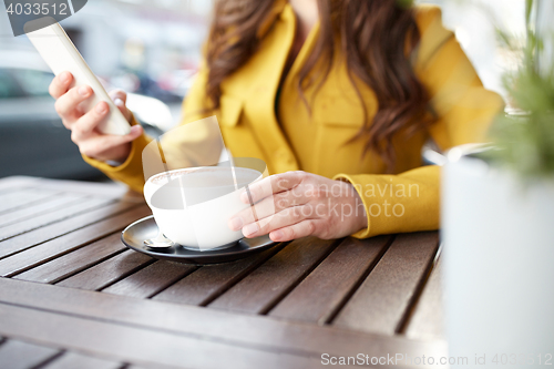 Image of close up of woman texting on smartphone at cafe