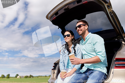 Image of happy couple with coffee at hatchback car trunk