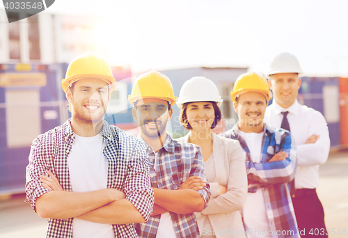 Image of group of smiling builders in hardhats outdoors