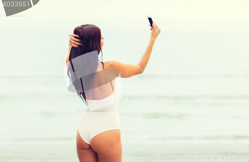 Image of young woman taking selfie with smartphone