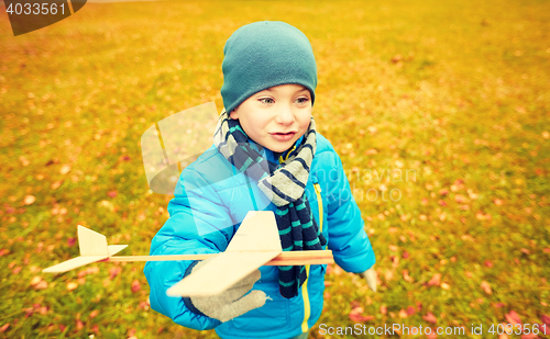 Image of happy little boy playing with toy plane outdoors