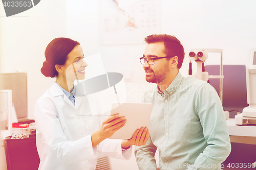 Image of optician with tablet pc and patient at eye clinic