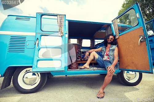 Image of smiling young hippie man in minivan car