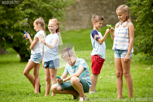 Image of kids with smartphones playing game in summer park