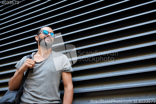 Image of man with backpack standing at city street wall