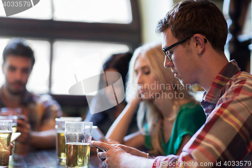 Image of friends with smartphones drinking beer and at pub