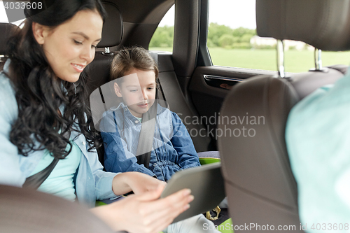 Image of happy family with tablet pc driving in car