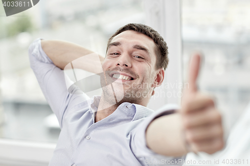 Image of smiling man showing thumbs up at home or office