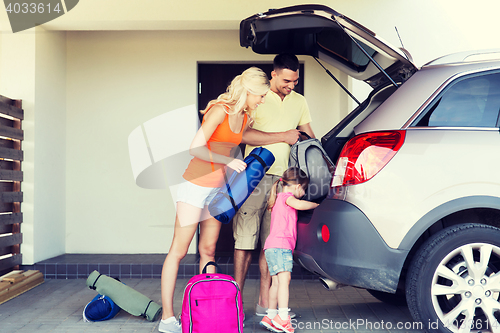 Image of happy family packing things to car at home parking