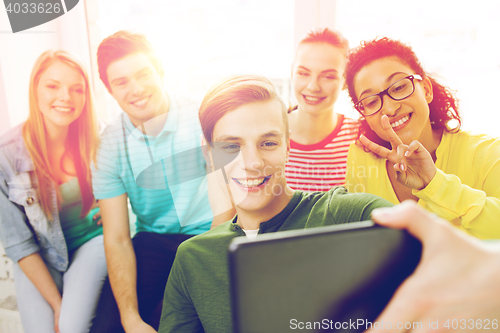 Image of smiling students making picture with tablet pc