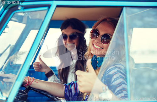 Image of smiling young hippie women driving minivan car