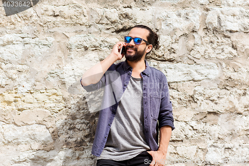 Image of smiling man with smartphone calling on city street