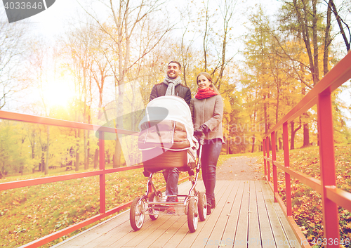 Image of smiling couple with baby pram in autumn park