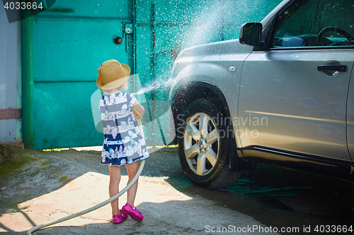 Image of Little girl helps her parents to wash the car