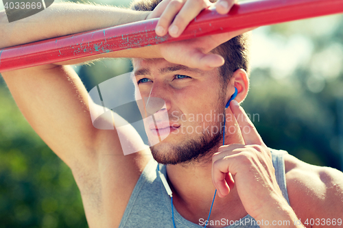 Image of young man with earphones and horizontal bar