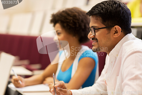 Image of group of students with notebooks in lecture hall