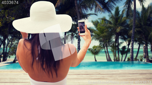 Image of woman taking selfie with smartphone on beach