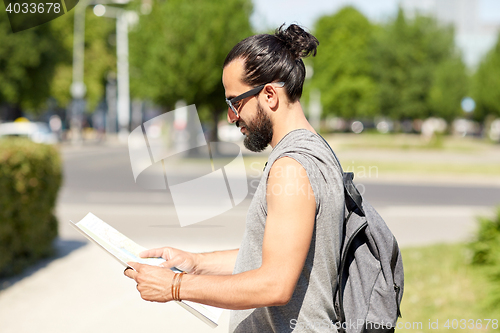 Image of man traveling with backpack and map in city