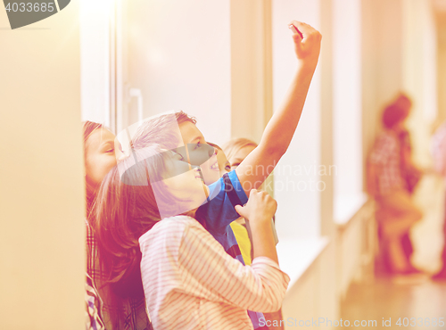 Image of group of school kids taking selfie with smartphone