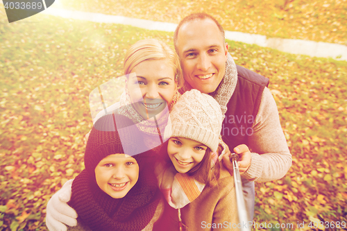 Image of happy family with selfie stick in autumn park