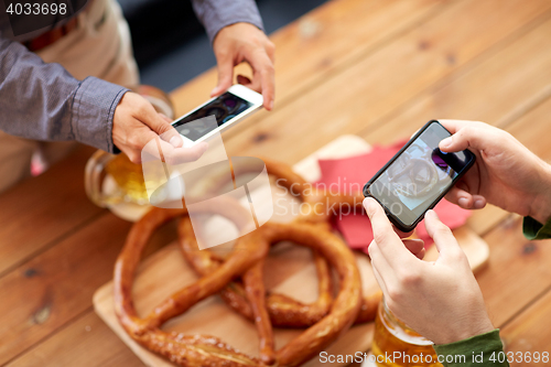 Image of close up of hands picturing pretzel by smartphone