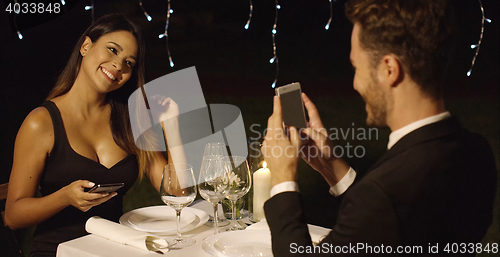 Image of Man in suit takes photo of beautiful dinner date