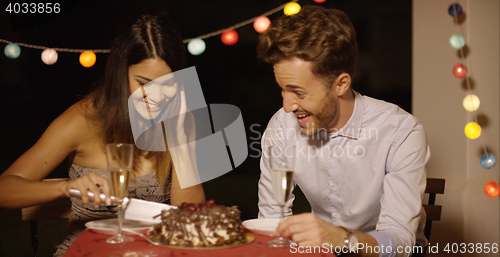 Image of Elated young couple joking as they cut the cake