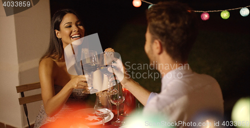 Image of Couple laughs as they raise their wine glasses