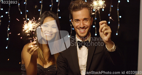 Image of Young couple celebrating new year with sparklers