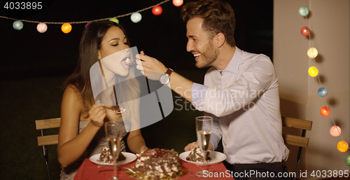 Image of Loving young man feeding his girlfriend cake